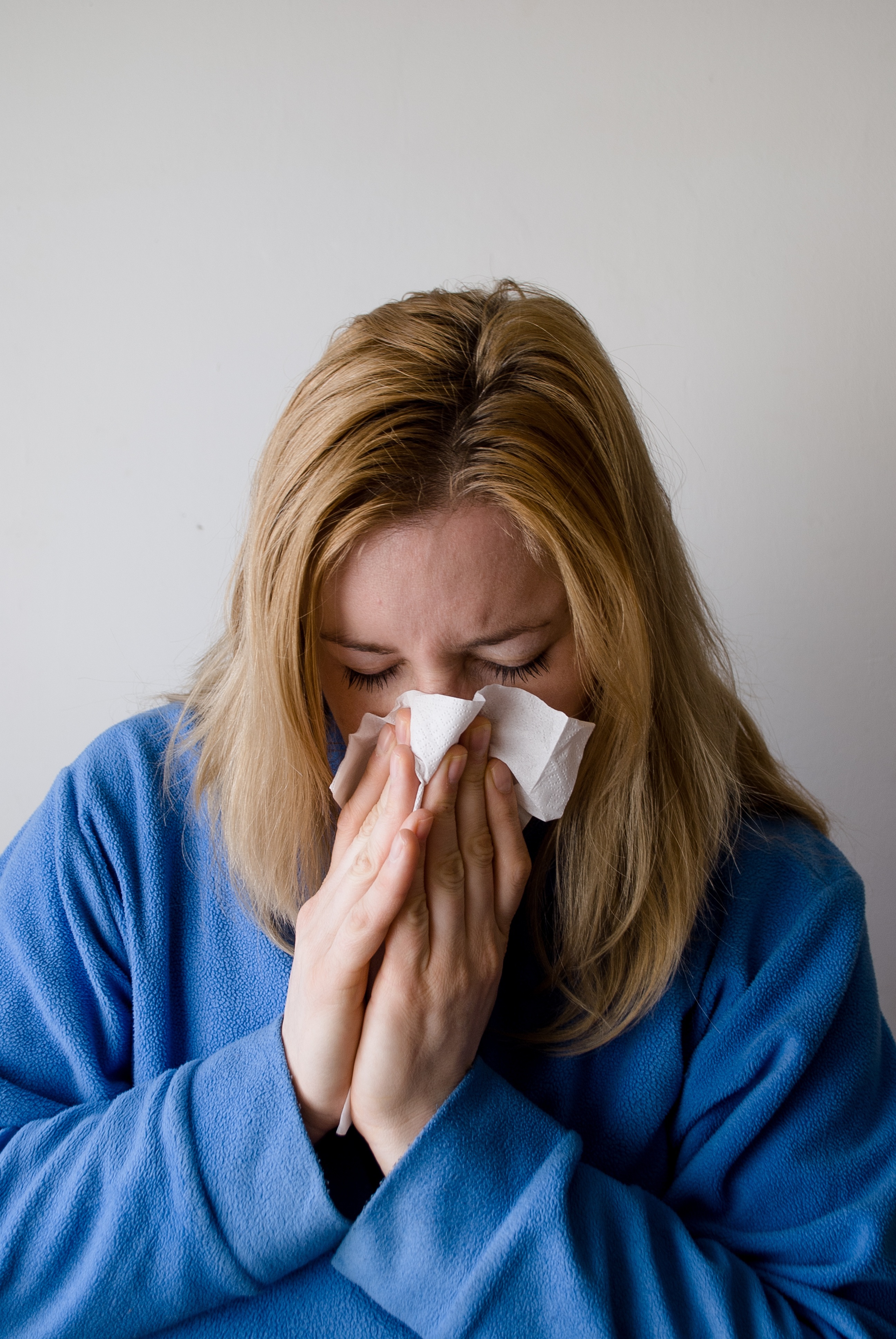 Woman blowing nose with tissue, symptom of common cold, pharmacist evidence-based cold guide